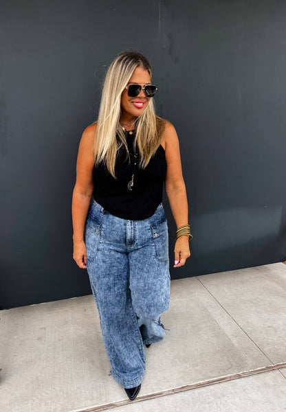 Blonde woman wearing Charlie Cinch Hem Wide Leg Jeans with a black sleeveless top and sunglasses, standing outdoors.