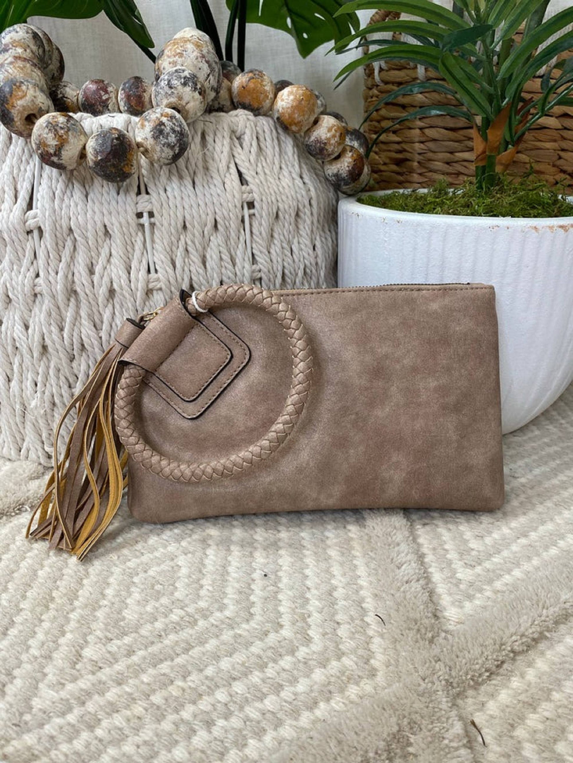 Stylish Leather Wristlet/Clutch featuring a braided strap and tassel, perfect for adding flair to any outfit.